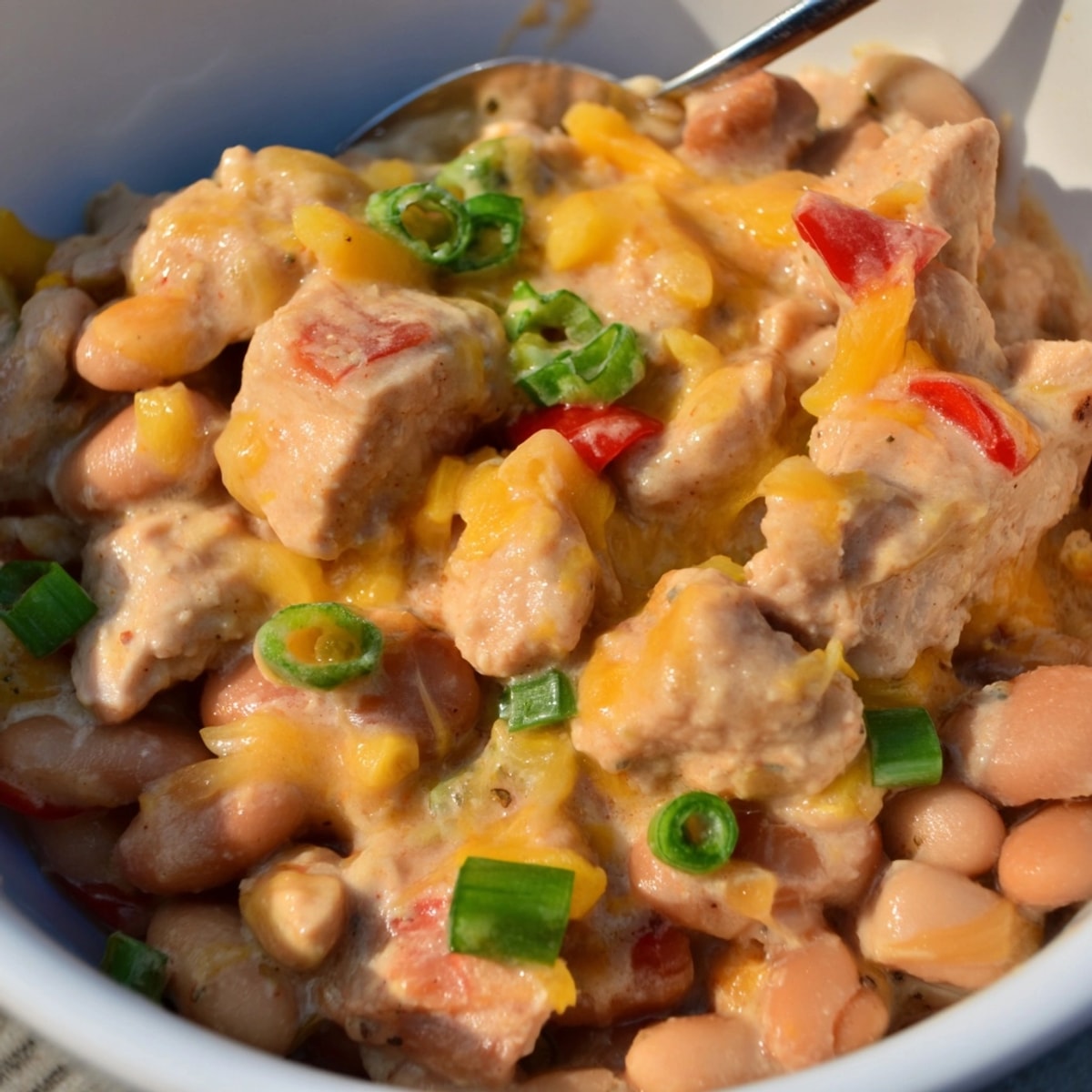 Close-up of Cajun Chicken Cheddar Pintos, bubbling hot and cheesy, with green onion garnish.