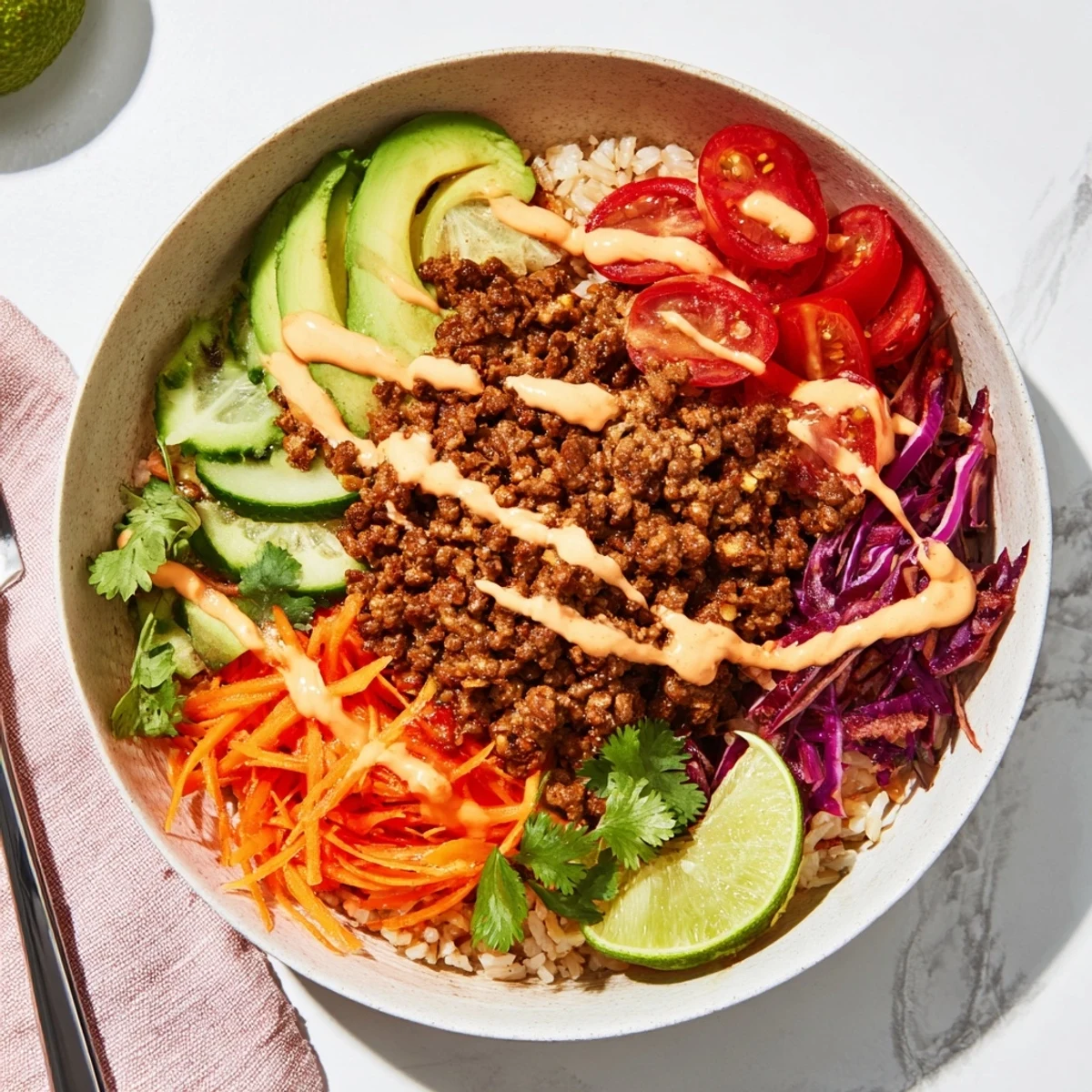 Hearty plant-based meat bowl with quinoa, fresh veggies, and a spicy mayo drizzle.