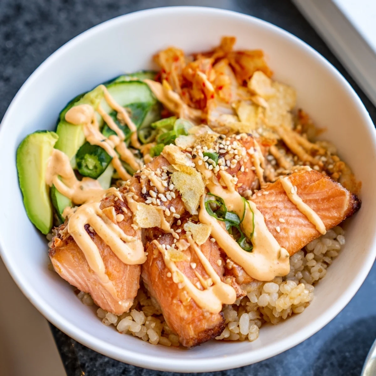 Savor the flavorful Crispy Salmon Rice Bowl bursting with garlic, cucumber, and tangy toppings.