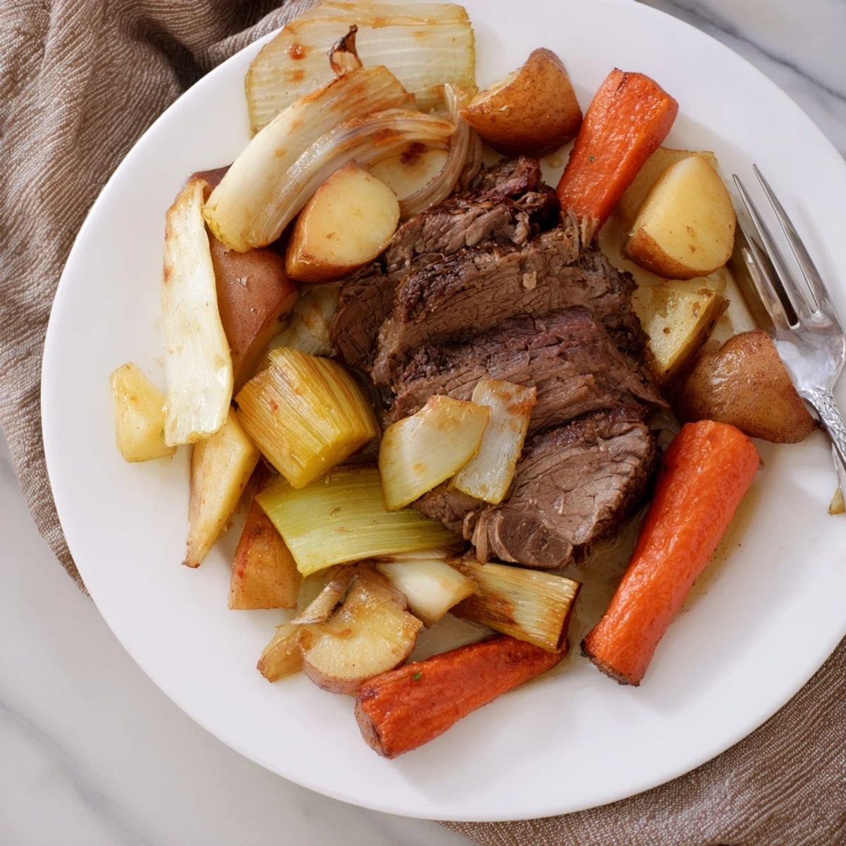 Tender Sunday Pot Roast with roasted veggies, served in a rich gravy alongside colorful, soft vegetables.