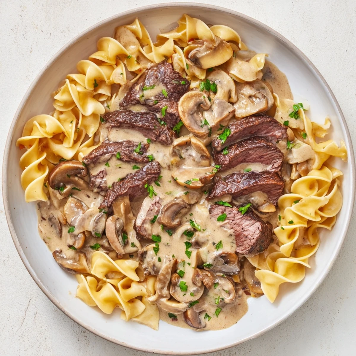 Enjoy a comforting bowl of warm Creamy Mushroom Beef Stroganoff, served steaming hot from the skillet.