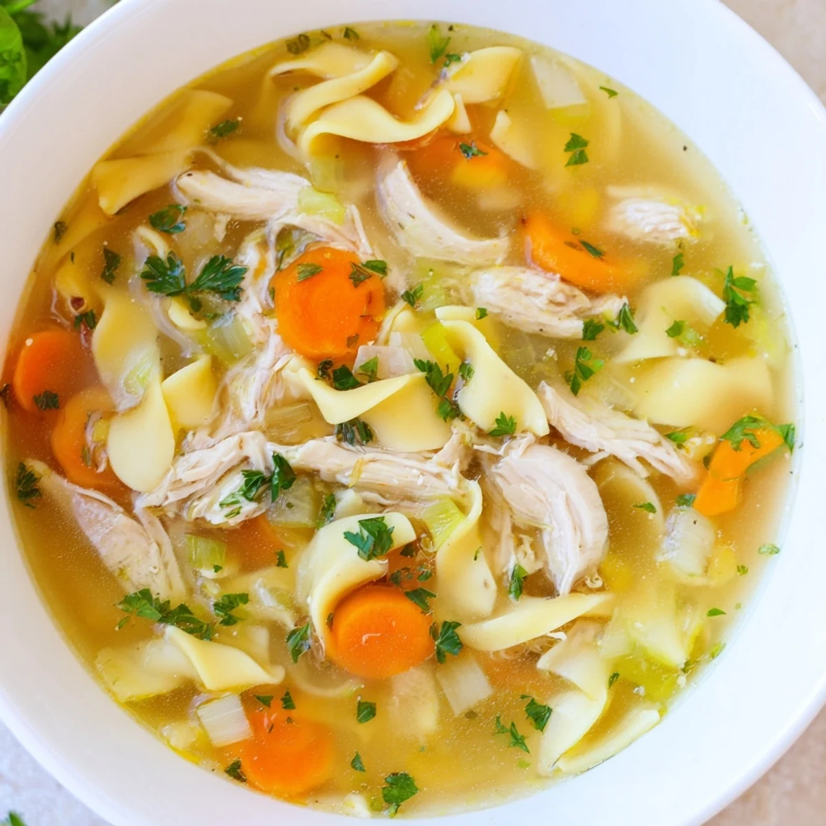 Steaming bowl of homemade chicken noodle soup, with tender chicken and golden egg noodles.