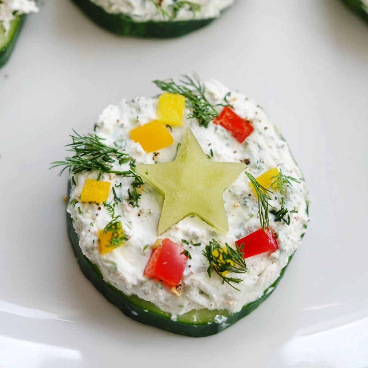 Holiday Star Cucumber Bites: Festive platter of cucumber bites with vibrant pepper garnish, cream cheese.