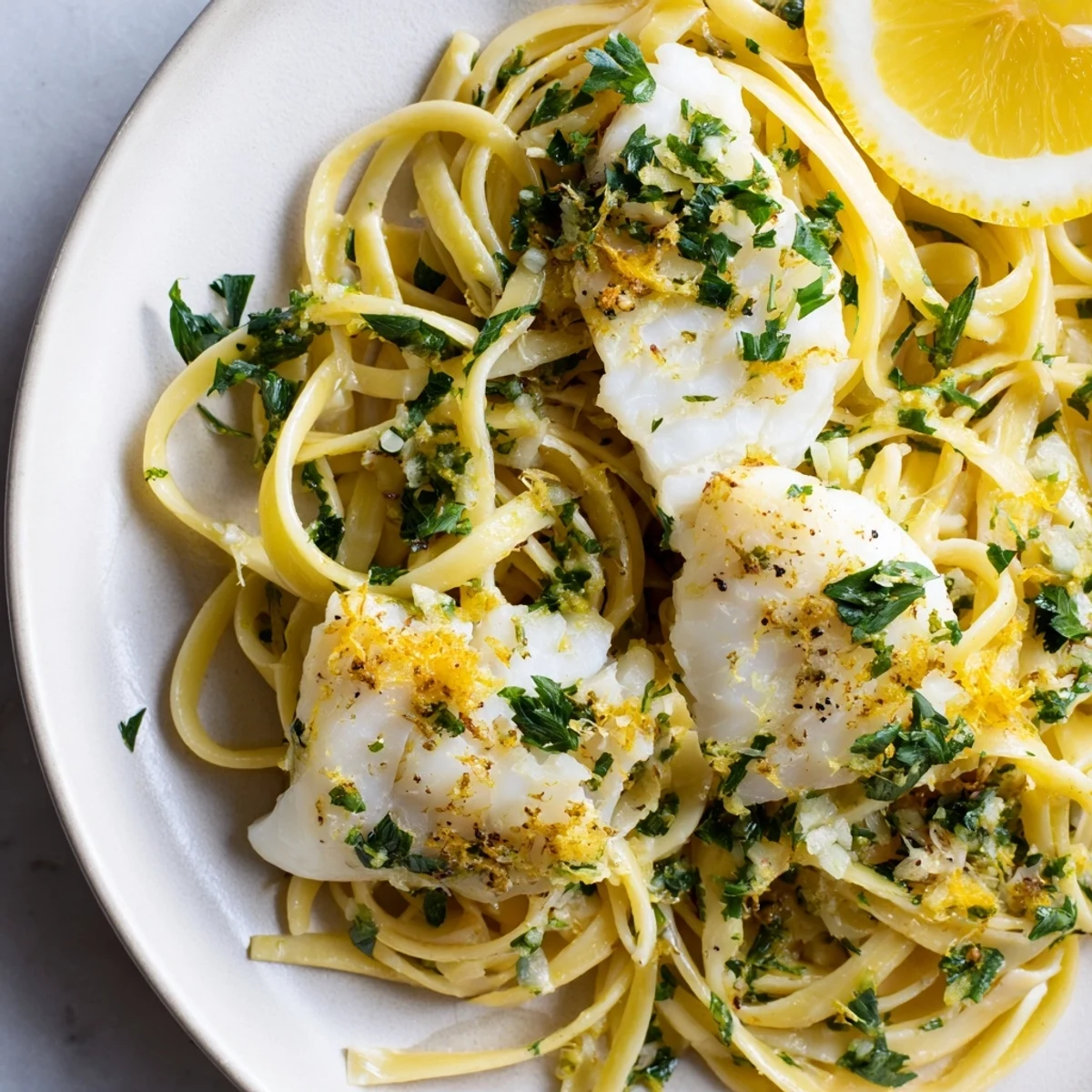 A close-up of finished Crispy Fish Pasta: golden fish, spaghetti, lemon, and fresh herbs combine.