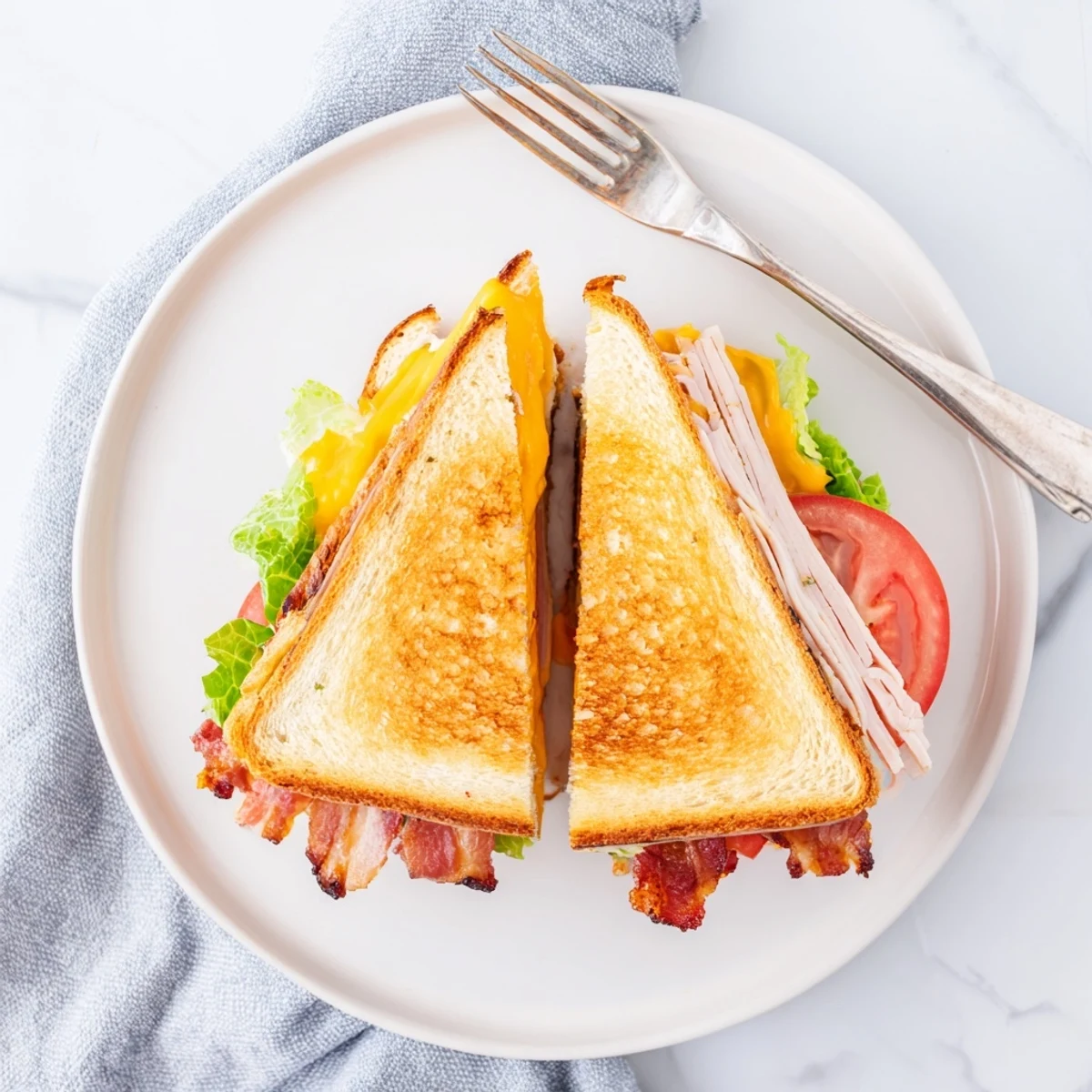 Buttery sourdough cradles the Turkey Club Grilled Cheese, with bacon and turkey peeking out beside a crisp salad garnish.