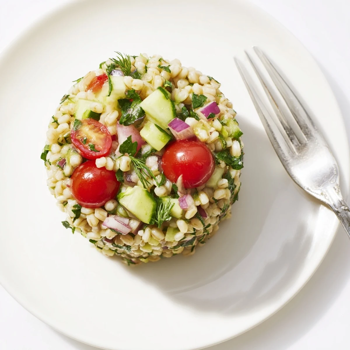 Brightly lit Barley and Herb Salad with diced cucumber, halved cherry tomatoes, and fresh herbs, perfect as a light vegetarian lunch or side.