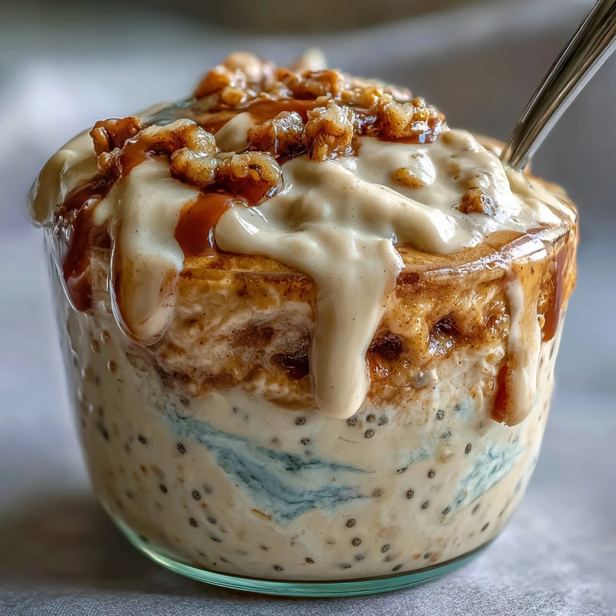 Overnight oats jar topped with cream cheese drizzle for High-Protein Cinnamon Roll Overnight Oats, a creamy high-protein breakfast.