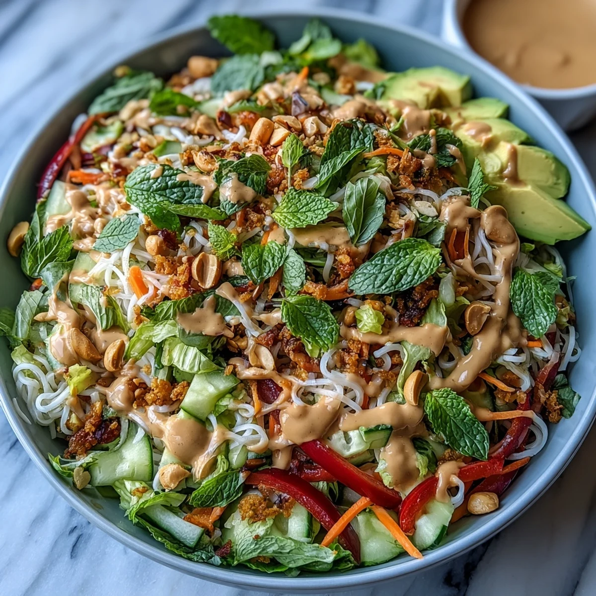 Colorful Vegan Spring Roll Salad tossed with crunchy vegetables, herbs, and rice noodles, served with a small bowl of peanut dressing.
