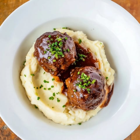 Tender BBQ Meatballs nestled on a bed of fluffy mashed potatoes, perfect for a cozy dinner.