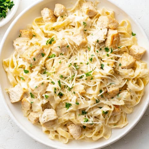 Golden, bubbly Chicken Fettuccine Alfredo Bake, fresh from the oven, ready for serving with garlic bread.