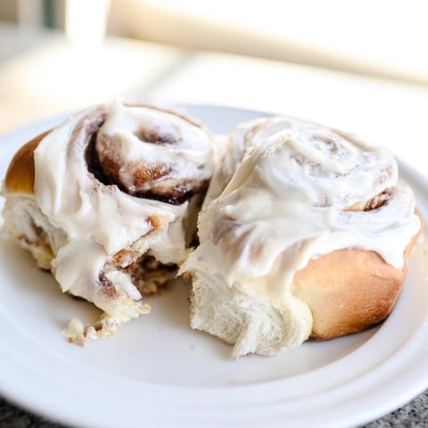 Warm, golden-brown Viral TikTok Heavy Cream Cinnamon Rolls, drizzled with creamy frosting and ready to eat.