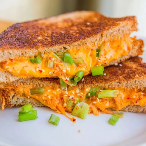 Golden, bubbly Skillet Kimchi & Cheddar Fusion Grilled Cheese, with melted cheese and kimchi oozing from the bread.