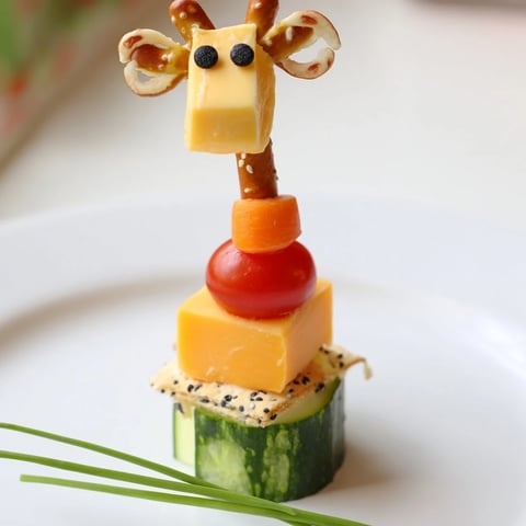 Vibrant Long-Necked Giraffe Snack Tower features colorful cheese and vegetable layers, a kid-friendly treat.