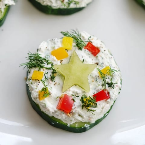 Holiday Star Cucumber Bites: Festive platter of cucumber bites with vibrant pepper garnish, cream cheese.