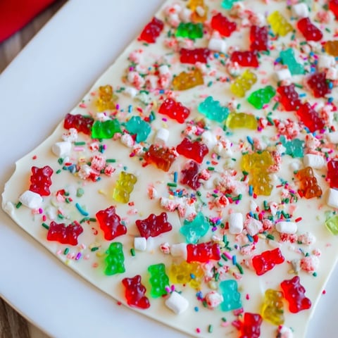 Colorful image: Gummy bears and candy canes scattered on white chocolate creates the perfect sweet treat.