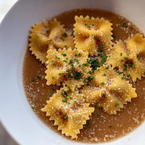 Crispy golden pasta chip cereal pieces in a bowl, swimming in flavorful parmesan broth.