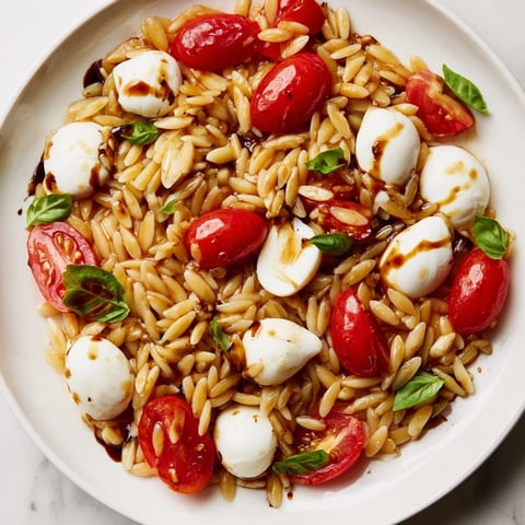 Vibrant Caprese Orzo Salad featuring juicy tomatoes, creamy mozzarella, and a refreshing balsamic dressing.