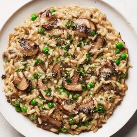 Steaming orzo mushroom risotto-style with creamy Parmesan cheese and fresh parsley, a vegetarian delight.