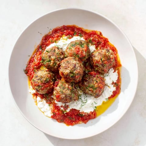Juicy Instant Pot Greek Meatballs glistening in a rich tomato sauce, ready to be topped with lemon-feta.