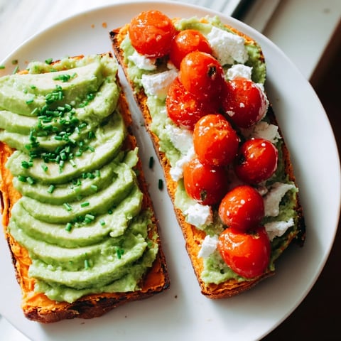 Golden roasted sweet potato slices topped with creamy avocado and fresh cherry tomatoes, showcasing a vibrant gluten-free breakfast.  