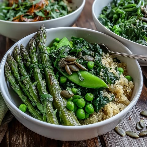 Vibrant Spring Green Bowl in a white bowl, featuring blanched peas, asparagus, and green beans over quinoa, drizzled with lemon dressing and topped with seeds.