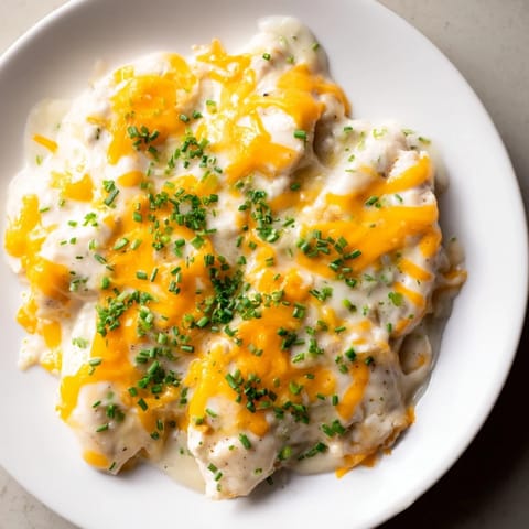 A close-up of a cheesy, creamy Cheddar Ranch Chicken Bake topped with chives.