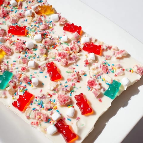 Bright photo: Festive gummy bears mixed with candy canes on set chocolate, ready to break and serve.