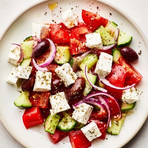 Freshly tossed Mediterranean salad, showcasing vibrant tomatoes, olives, and a zesty dressing.
