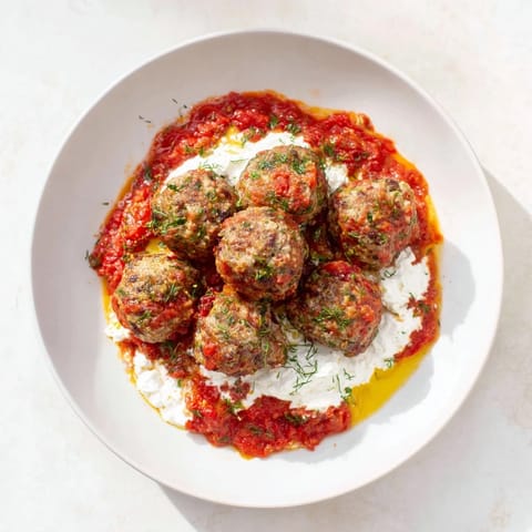 Juicy Instant Pot Greek Meatballs glistening in a rich tomato sauce, ready to be topped with lemon-feta.