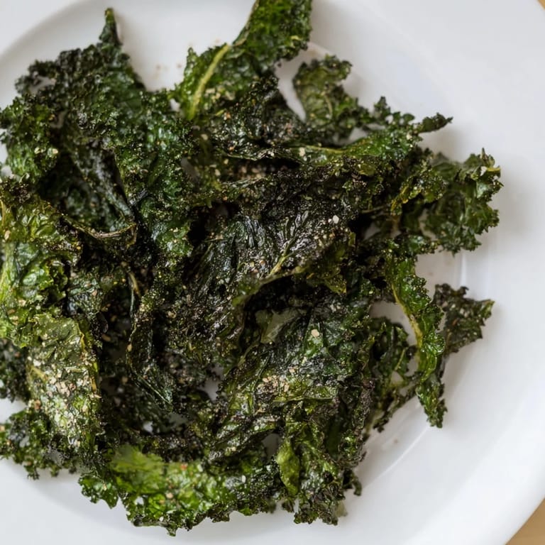 A bowl of golden, baked kale chips; a vegan, gluten-free snack with smoky paprika.