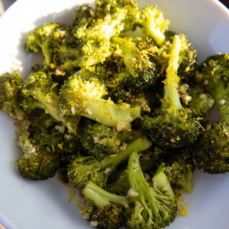 Crispy-edged Lemon Garlic Roasted Broccoli piled ready to serve with a bright lemon garnish.