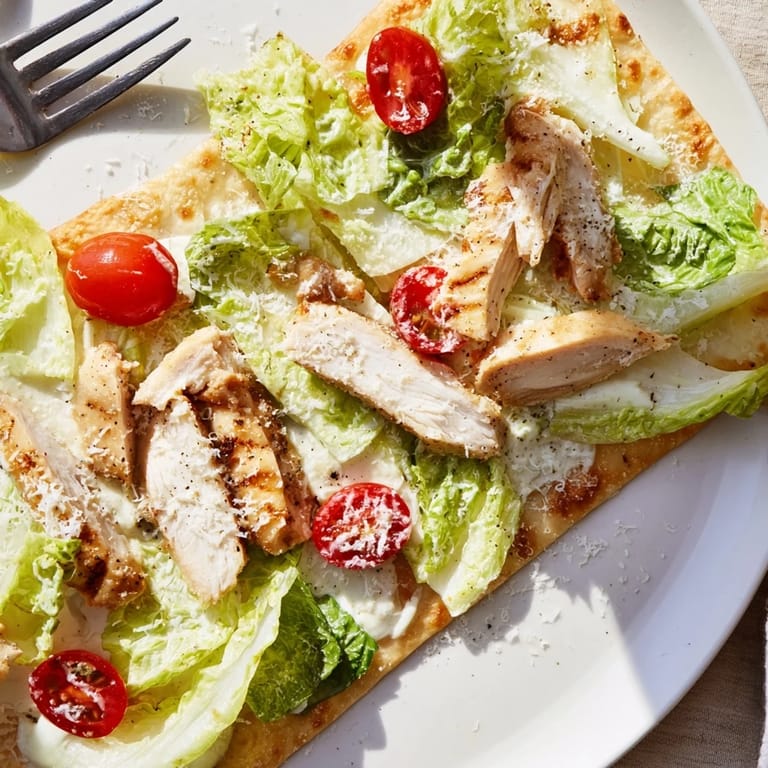 Caesar Chicken Flatbread on a rustic board, ready to serve with extra dressing and tomatoes for added flavor.