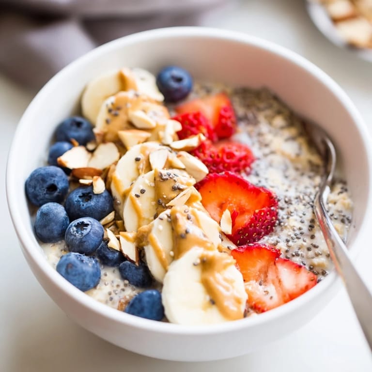 Enjoy a creamy serving of overnight oats with chia seeds, garnished with ripe banana slices and a sprinkle of blueberries for a fresh morning start.