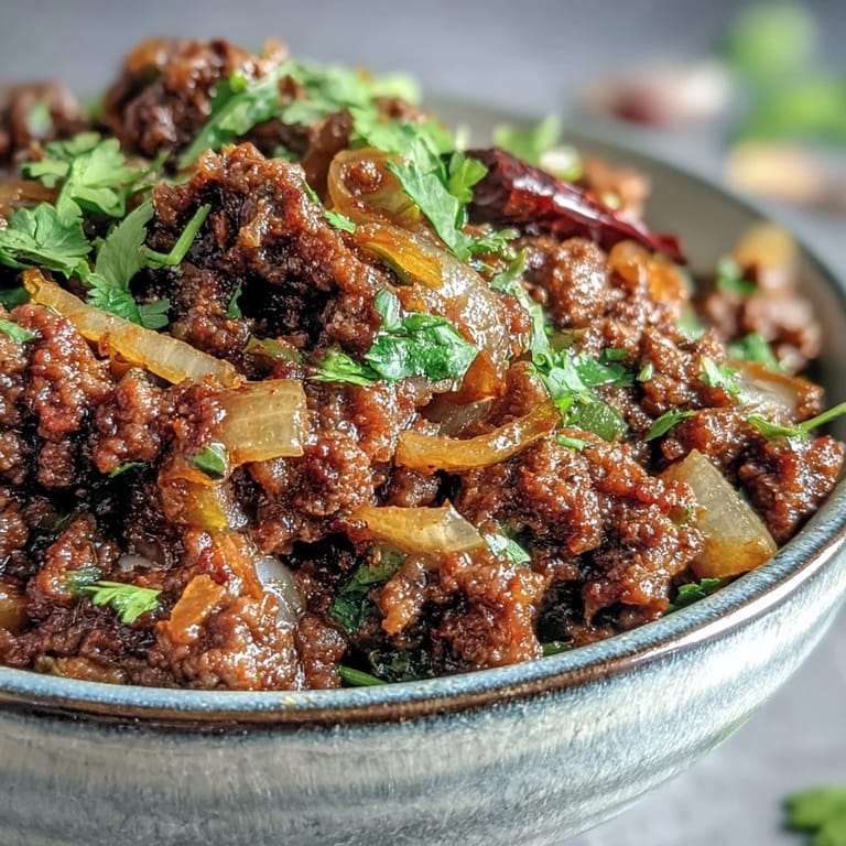 Aromatic Venison Keema Curry simmering in a pan, featuring tender ground meat and diced tomatoes.
